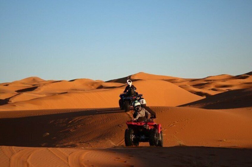 A person riding a quad bike on a desert dune. 1
