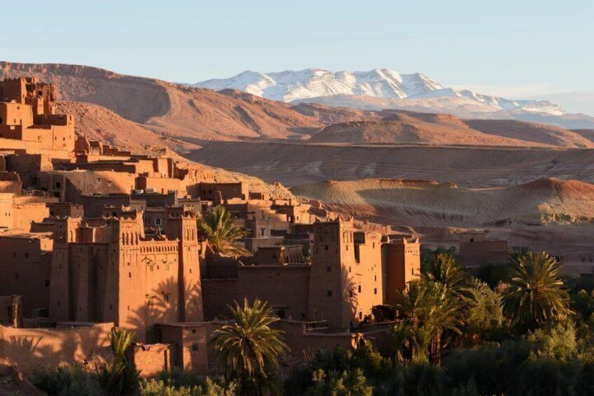 A desert town with adobe buildings, palm trees, and snow-capped mountains in the background. 5