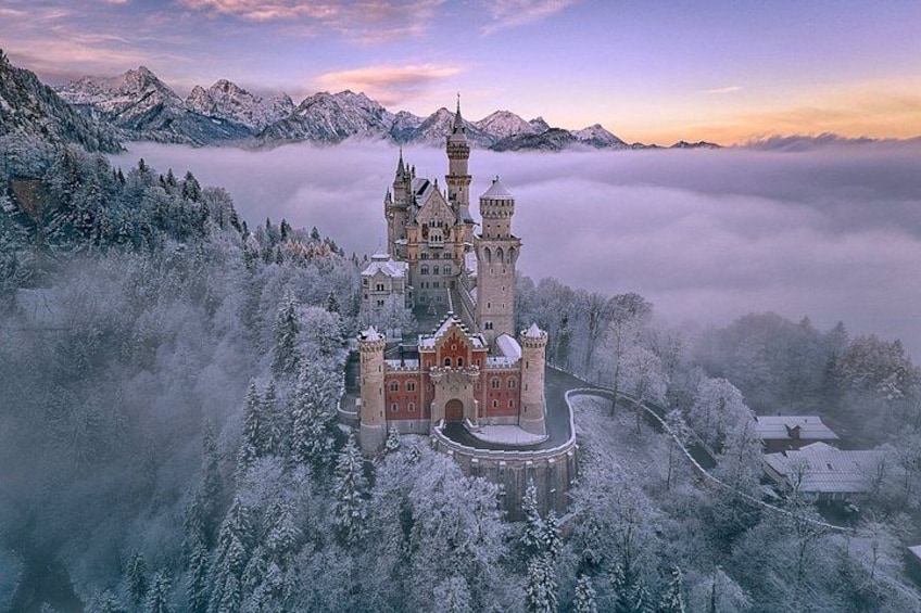 A castle surrounded by snow-covered trees and mountains. 3