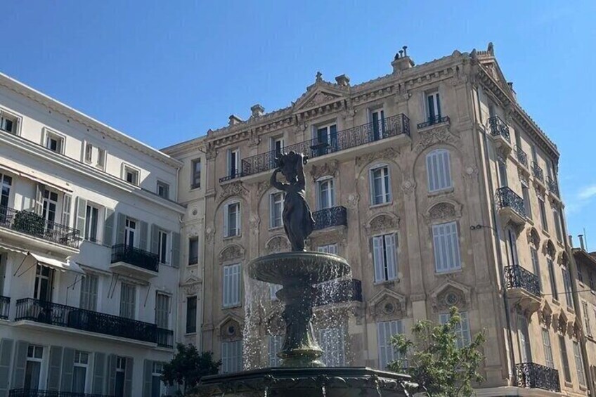 Une fontaine classique, ornée d’une statue au centre, et entourée de bâtiments historiques dotés de balcons richement décorés. 1
