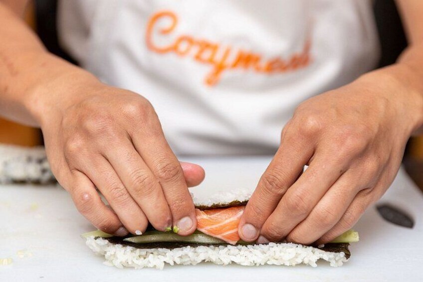Handen bereiden sushi met rijst, zeewier en zalm. 1