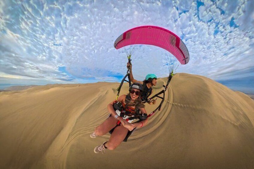 A person paragliding over a sand dune landscape. 5