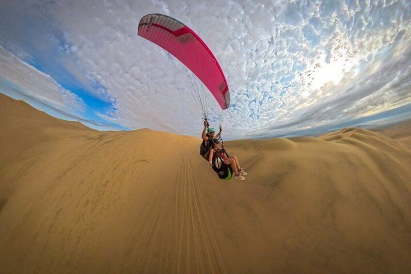 A person paragliding over a vast desert landscape. 4