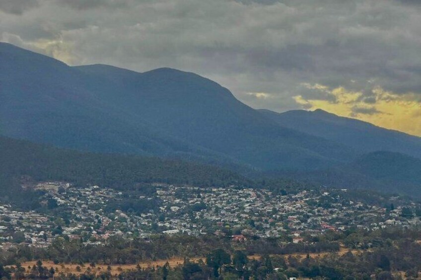 A mountainous landscape with a town in the foreground and a cloudy sky. 2