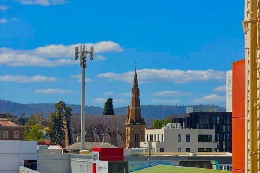 A church spire, a modern building, and a cell tower in a cityscape with a clear sky. 4