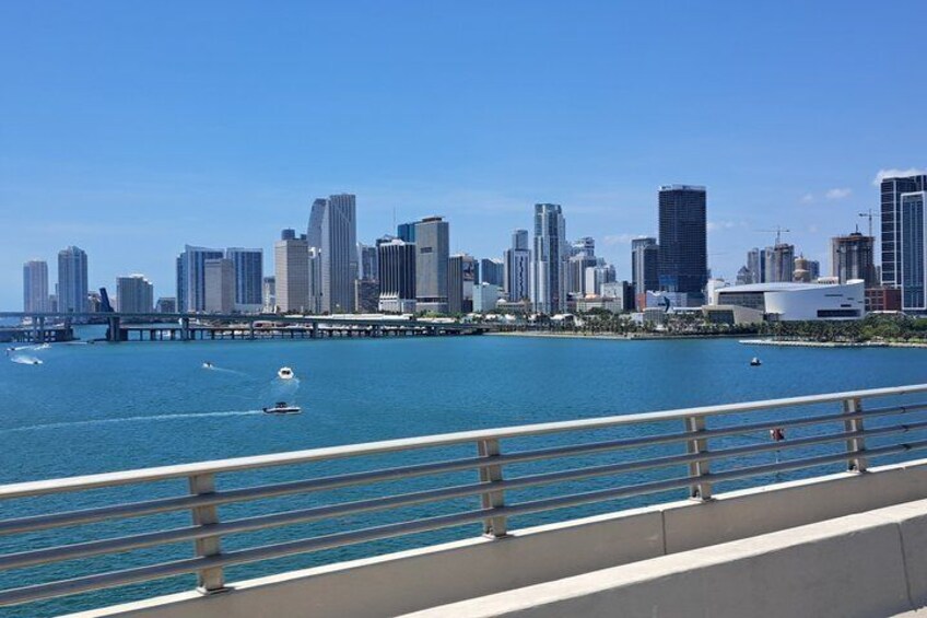 A city skyline with high-rise buildings, a bridge, and a waterfront with boats. 3