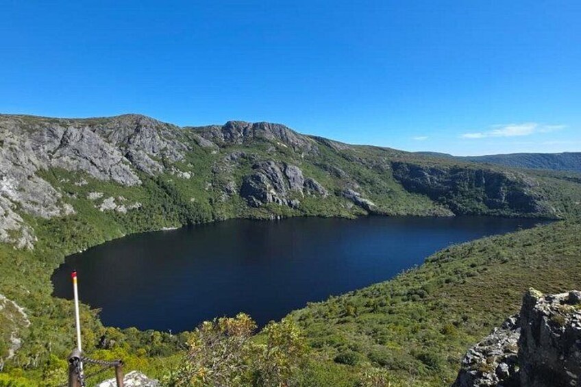 A lake surrounded by mountains, a clear sky, and a hiking trail. 5