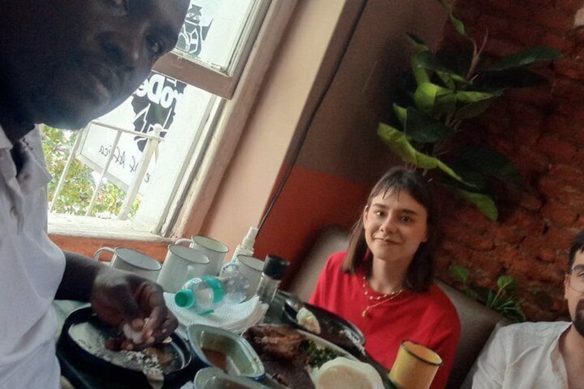 A person serving food at a table with a window view, a plant, and a menu in the background. 3