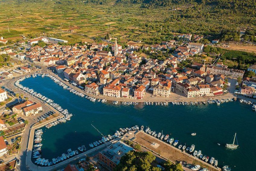An aerial view of a coastal town with a marina, buildings, and surrounding greenery. 4