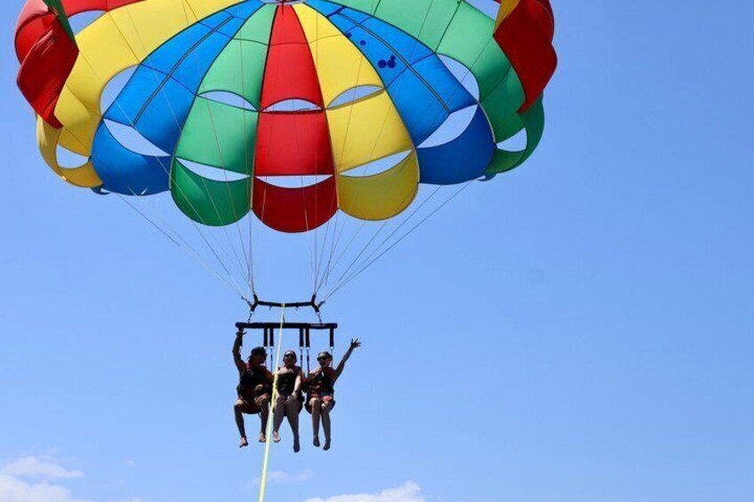 A parachute with multiple colors, a clear blue sky, and a person in a harness. 2