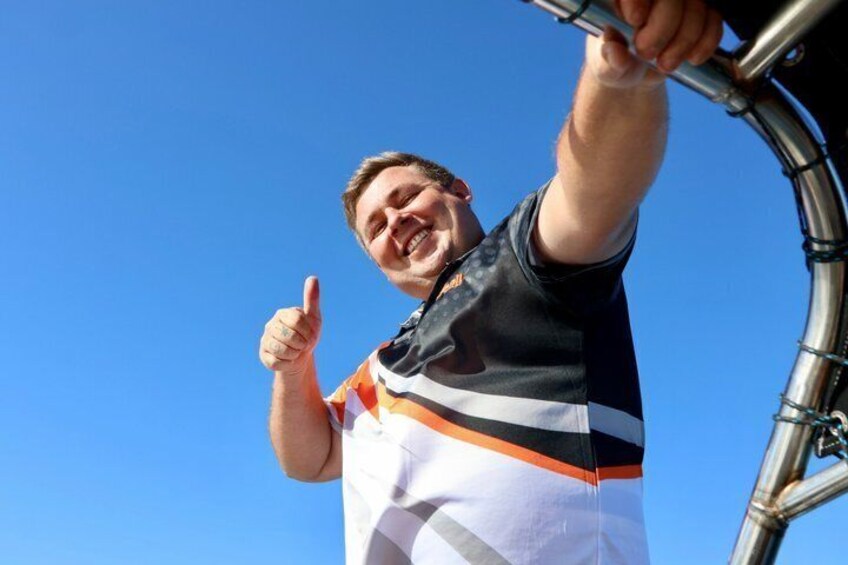 A person giving a thumbs-up gesture while holding onto a bicycle handlebar. 4
