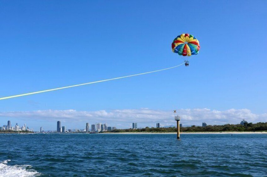 A parasail over water with a city skyline in the background. 1