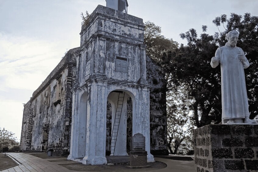 A weathered historical building with a statue of a man. 4