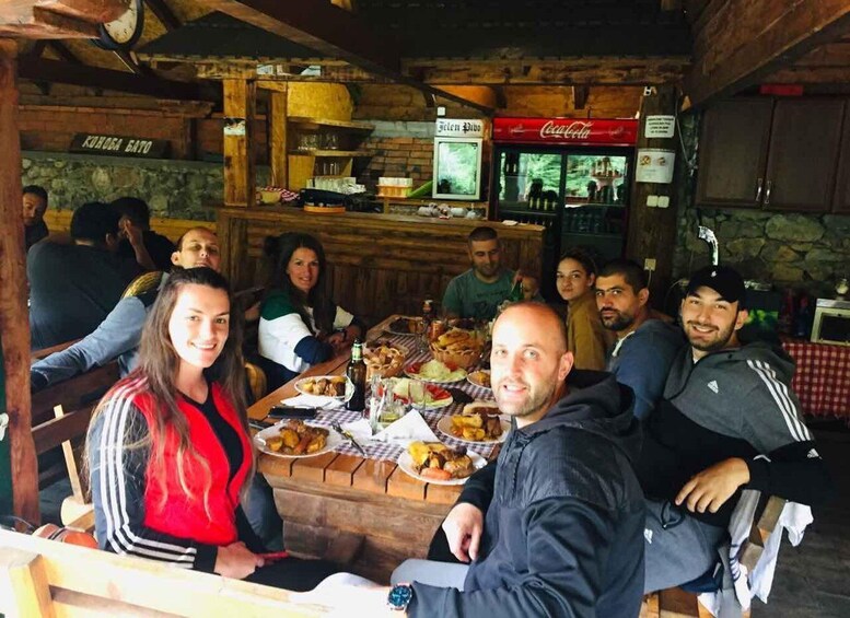 A group of people dining in a rustic restaurant with wooden interiors and a Coca-Cola refrigerator. 2