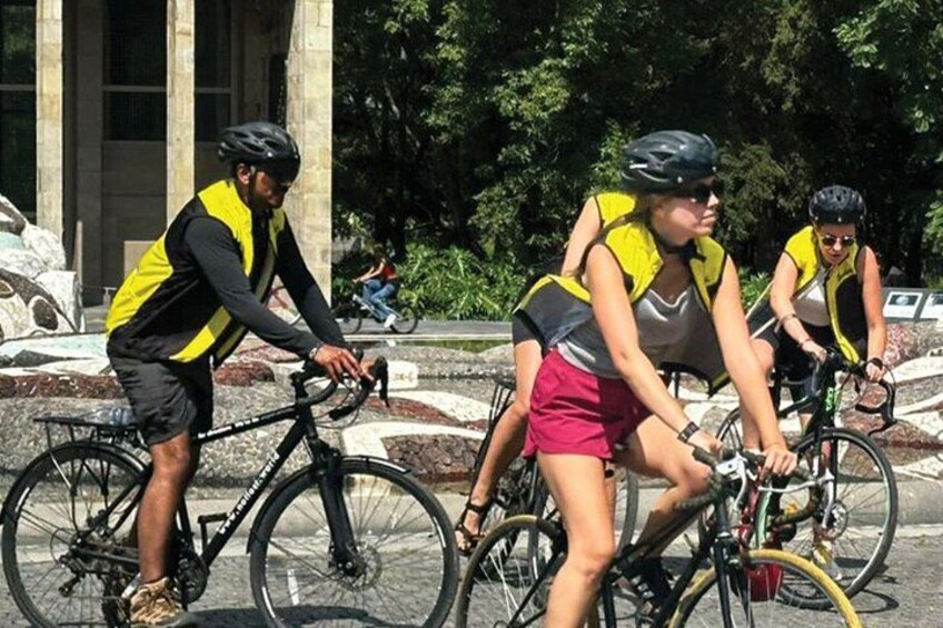 Cyclists wearing safety vests riding on a paved path. 2