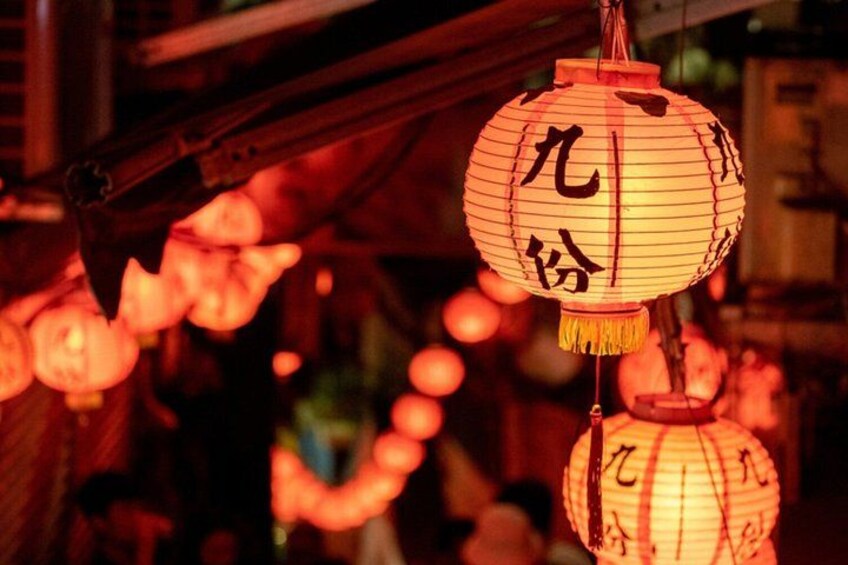 A traditional lantern with Chinese characters, hanging in a dimly lit setting. 1