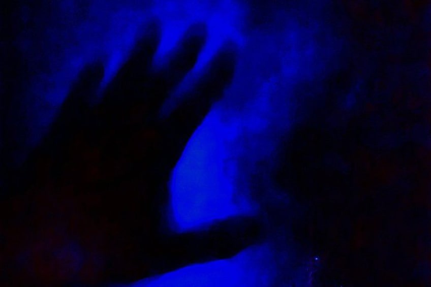 A hand reaching out in a dark environment with blue lighting. 2
