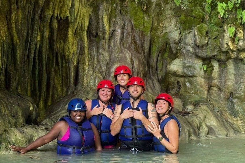 A group of people in a cave with water, wearing helmets and life vests. 1