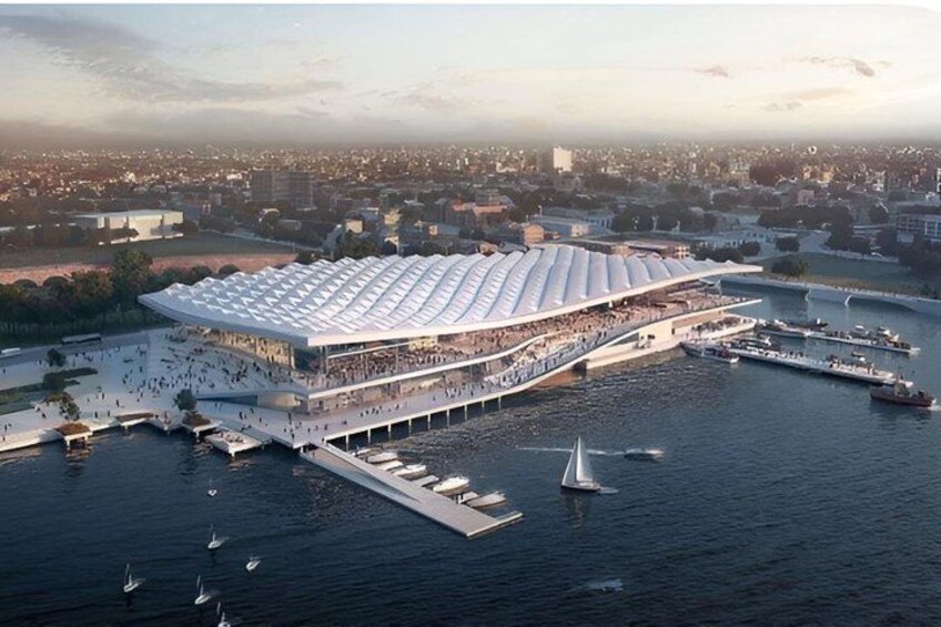 A waterfront stadium with a large, white, curved roof and a dock extending into the water. 2