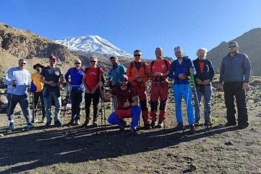 A group of people standing on a mountain with a snow-capped peak in the background. 4