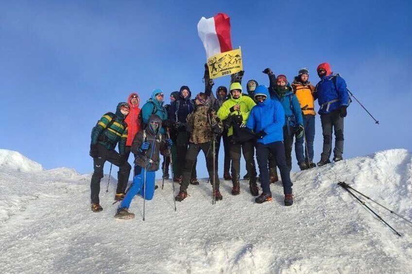 A group of people on a snowy mountain with a flag. 1