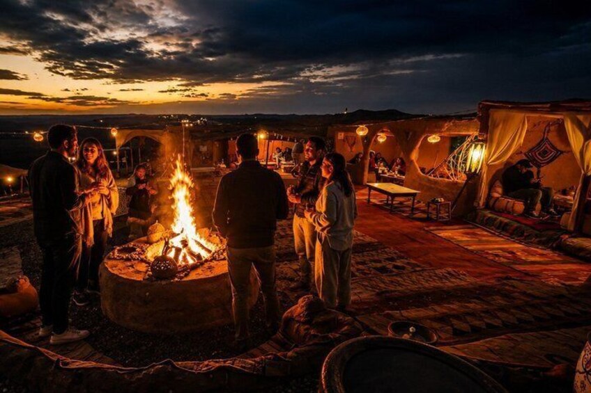A group of people around a campfire at dusk. 1