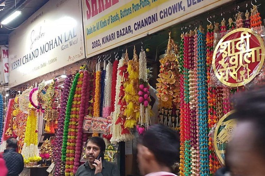 A market stall with colorful beaded necklaces and a sign for Kesrichand Mohan Lal. 1