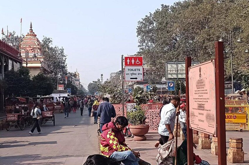 A busy street with pedestrians, a temple, and a signboard. 2