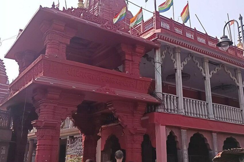 A red temple with intricate carvings and multiple flags. 4