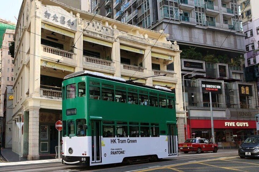 A green and white double-decker bus on a city street with buildings in the background. 4