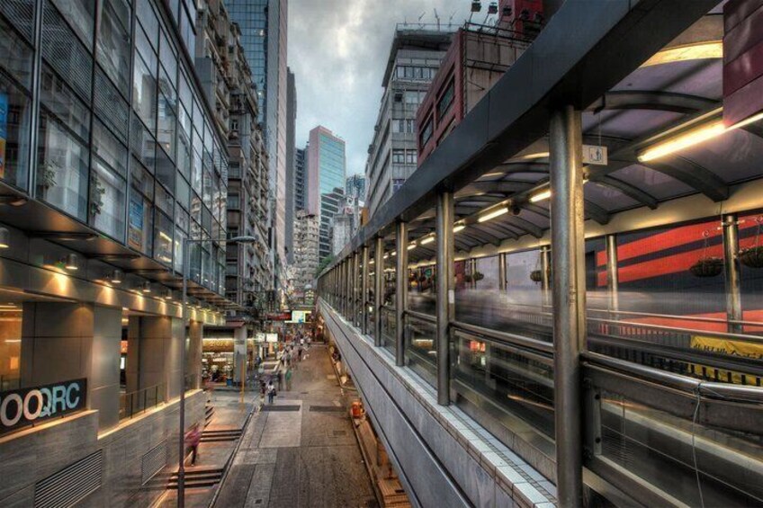 A train station with a modern train, glass buildings, and a busy urban environment. 2