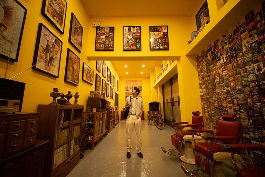A hallway with yellow walls, framed pictures, and red chairs. 4