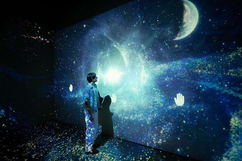 A person in a white suit standing in front of a space-themed projection. 5