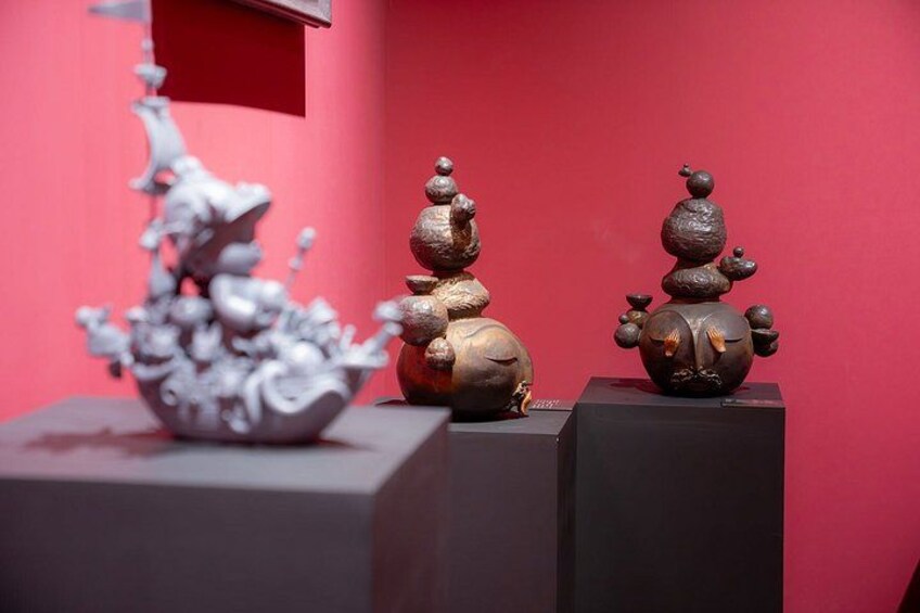 Three sculptures on pedestals against a red background. 3