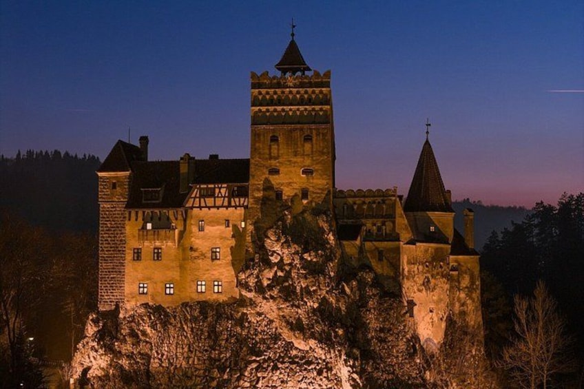 A castle with a prominent tower, surrounded by rocky terrain and trees. 1