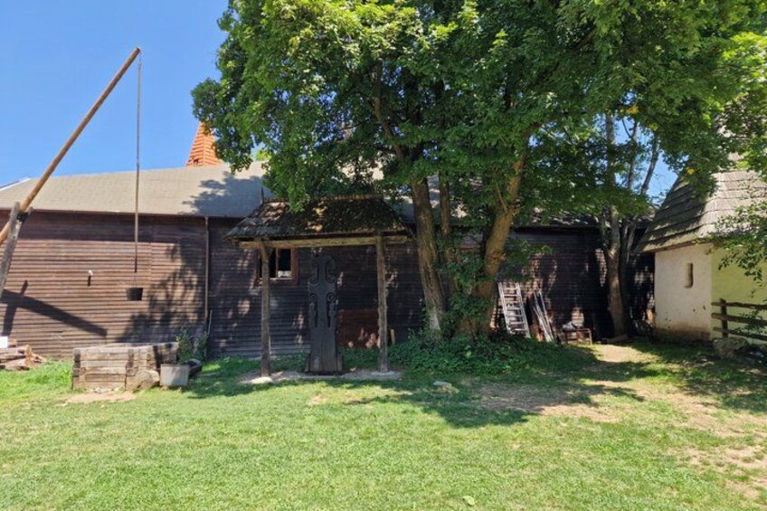 A rustic barn with a wooden door, a ladder, and a tree in the foreground. 5