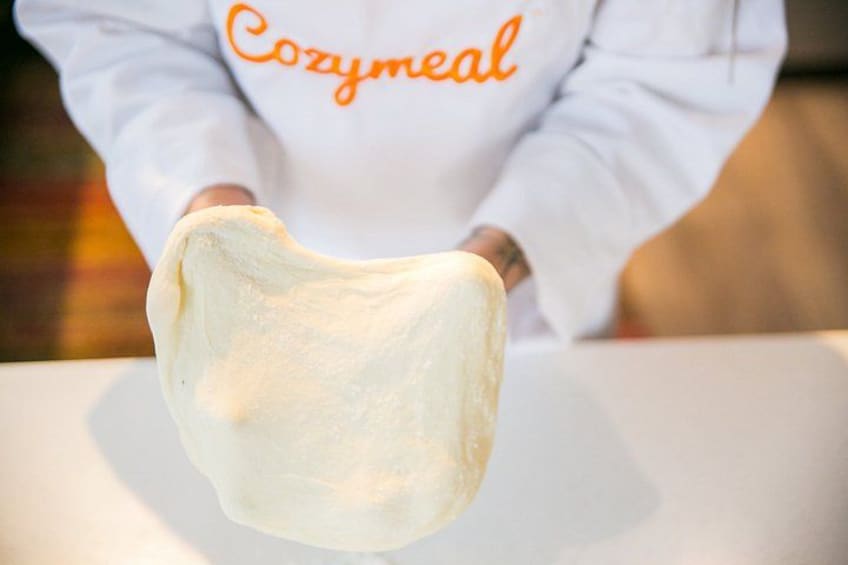 A person holding a large piece of dough. 1