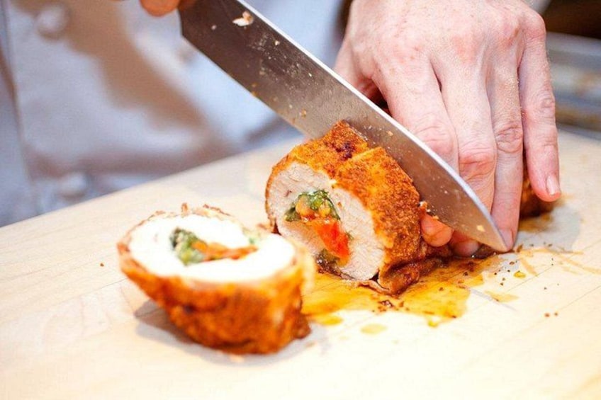 Una persona cortando un plato de carne rellena sobre una tabla de madera. 2
