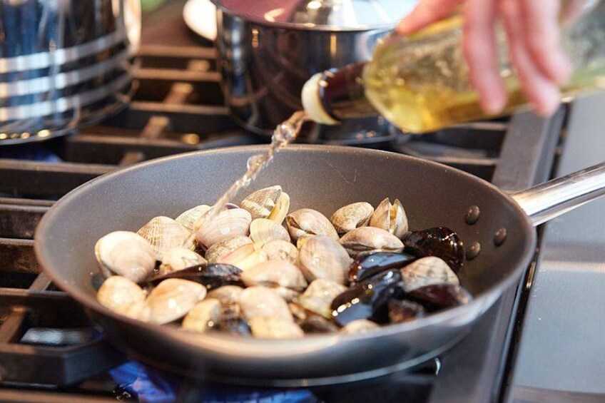Una sartén sobre la hornilla con almejas cocinándose. 3
