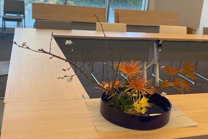 A wooden table with a dark blue vase containing a floral arrangement. 3