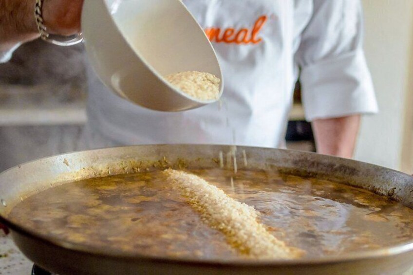 A person pouring a white powder into a pan with a liquid. 3
