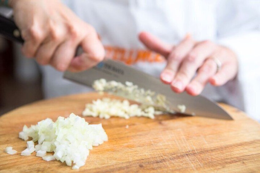 A person chopping onions on a wooden cutting board. 4