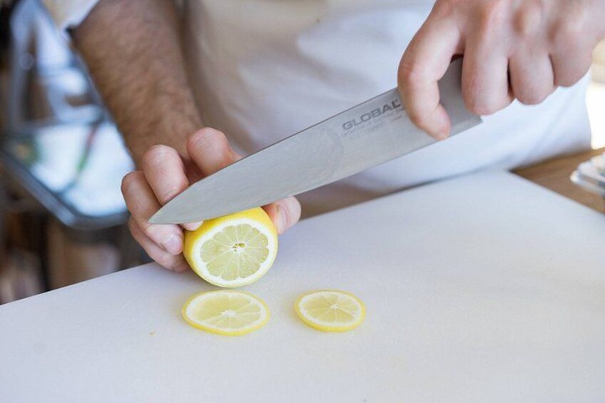 Una persona taglia un limone su un tagliere bianco. 2