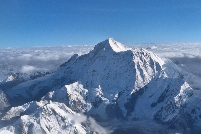 A snow-covered mountain peak with sharp ridges and a clear blue sky above. 1