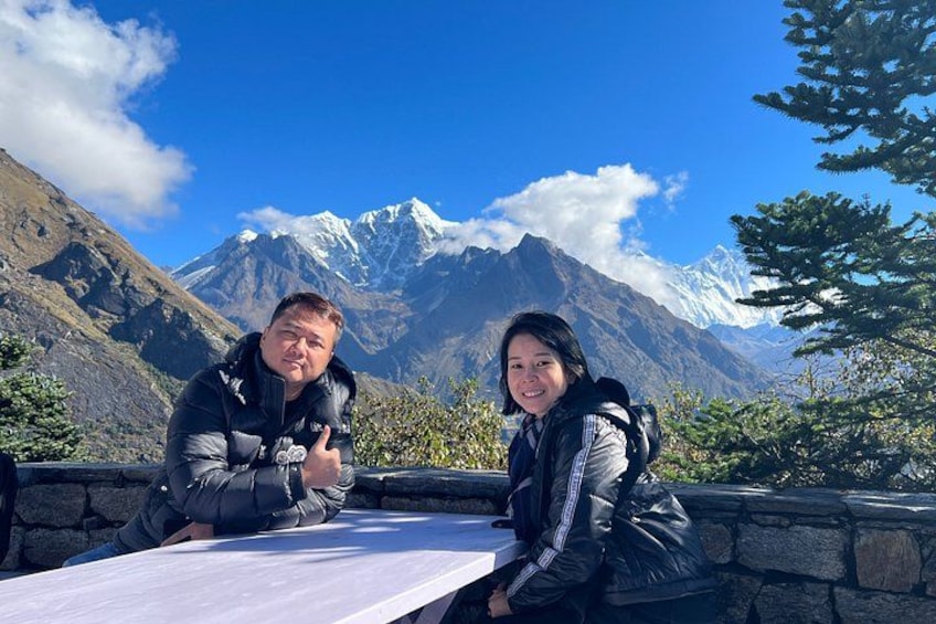 Two people sitting at a table with a mountain landscape in the background. 3