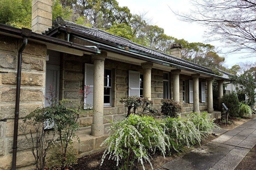 Un edificio de piedra con un porche, columnas y contraventanas. 3