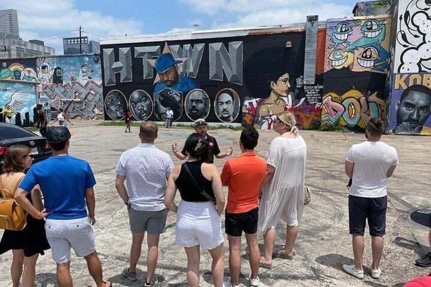 A group of people standing in front of a large mural with the word 'HTW' prominently displayed. 4