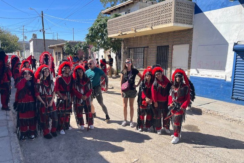 A group of people in traditional red and black attire, standing on a street. 5