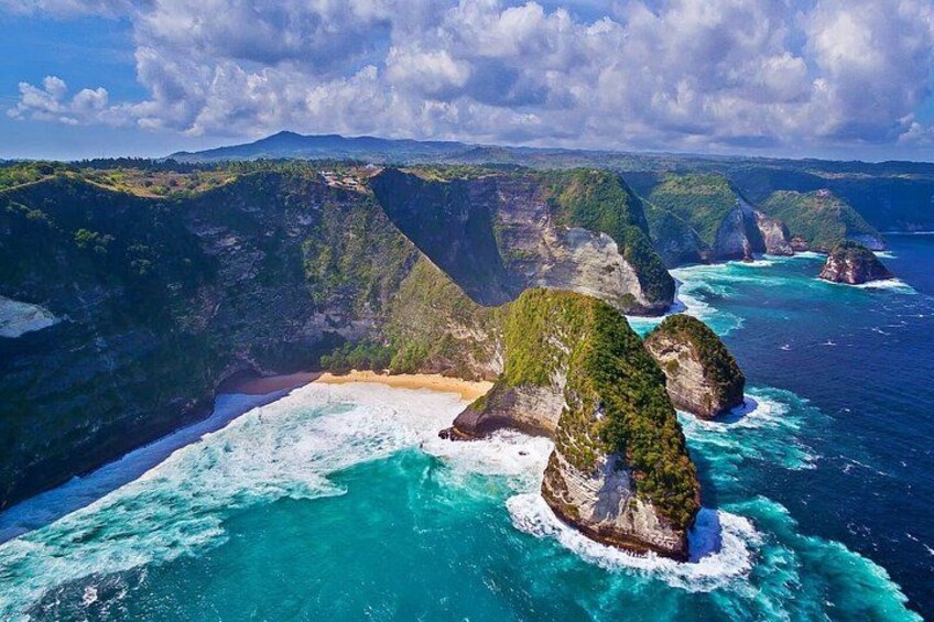 A coastal landscape with cliffs, turquoise waters, and a sandy beach. 3
