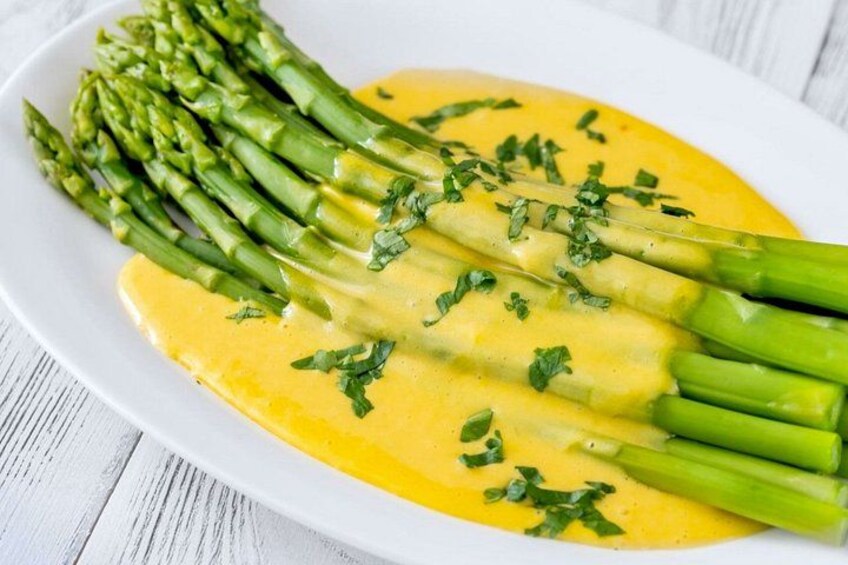 Une assiette d’asperges nappées d’une sauce jaune et parsemée d’herbes hachées. 2